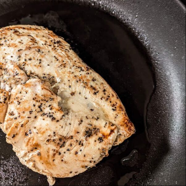 Lemon Pepper Chicken Breast browning in a dark pan